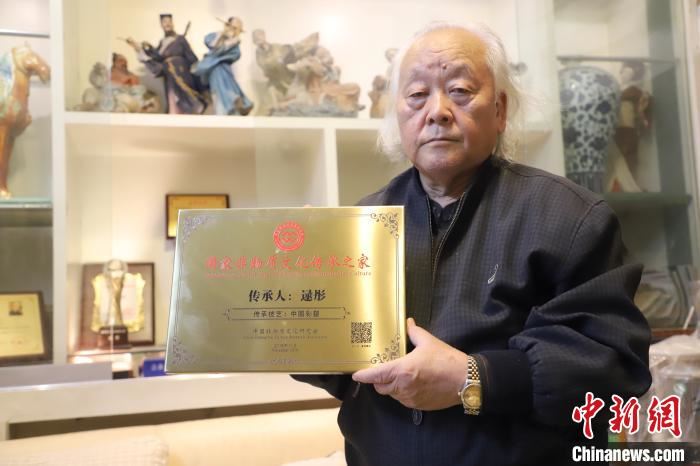 逯彤展示非遗传承人牌匾,身后是其作品。 张道正 摄 逯彤展示非遗传承人牌匾,身后是其作品。 张道正 摄