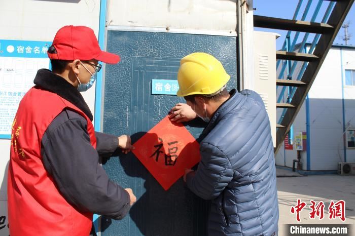 就地过年农民工和英志愿者一起贴福字。　中建五局供图 摄